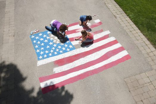 Girls with chalk coloring American flag on sidewalk Girls with chalk coloring American flag on sidewalk