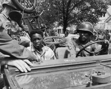 1957:  Caucasian National Guardsmen give an African-American student and his bicycle a lift to school while enforcing desegregation at Central High School in Little Rock, Arkansas. A cameraman and a crowd watch from the sidewalk.  (Photo by Paul Slade/Hulton Archive/Getty Images)