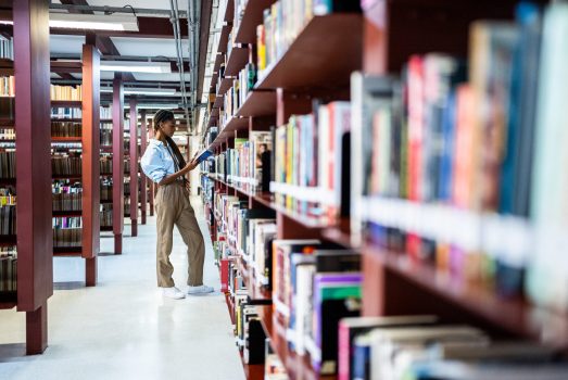 Young woman searching books in the library Young woman searching books in the library