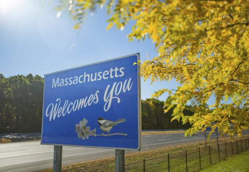 Massachusetts Welcome sign on the state line, on the side of the interstate, framed by colorful fall foliage typical of New England in autumn