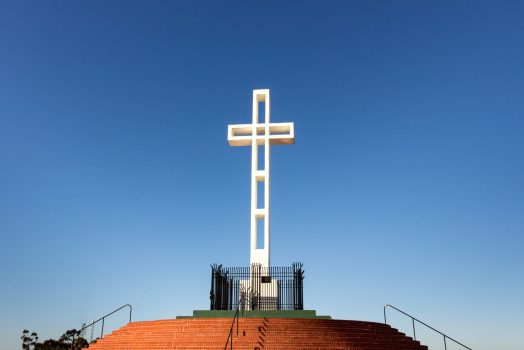 a white cross on a staircase with Mount Soledad in the background