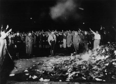 May 1933:  German soldiers and civilians give the Nazi salute as thousands of books smoulder during one of the mass book-burnings implemented throughout the country to destroy non-Aryan publications.  (Photo by Keystone/Getty Images)