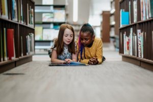 Young girls reading a library book together inside