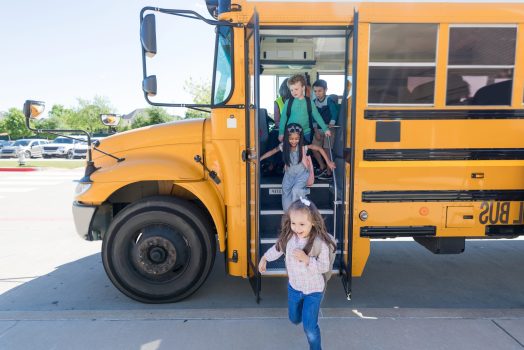 A group of elementary school children exit bus at the end of the school day.