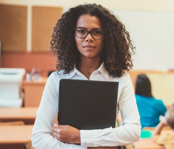 Back to school Portrait of mixed race teacher in class standing serious during exam