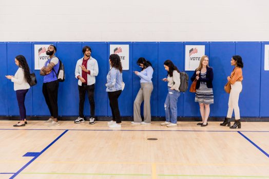 Diverse group of voters stand in line waiting to be assigned to a booth Diverse group of voters stand in line waiting to be assigned to a booth