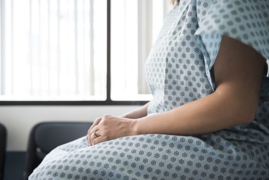 Midsection of female patient waiting in hospital exam room